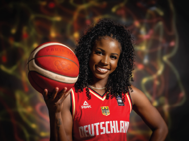 women wearing basketball jersey posing with olympic basketball
